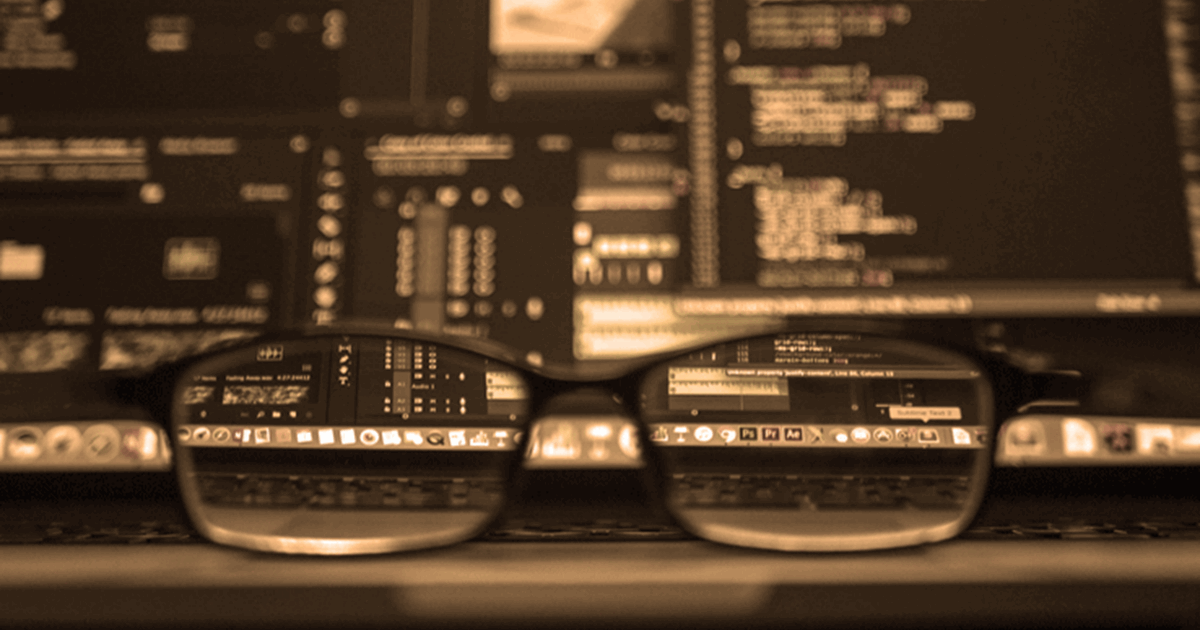 Glasses in front of programming code on laptop