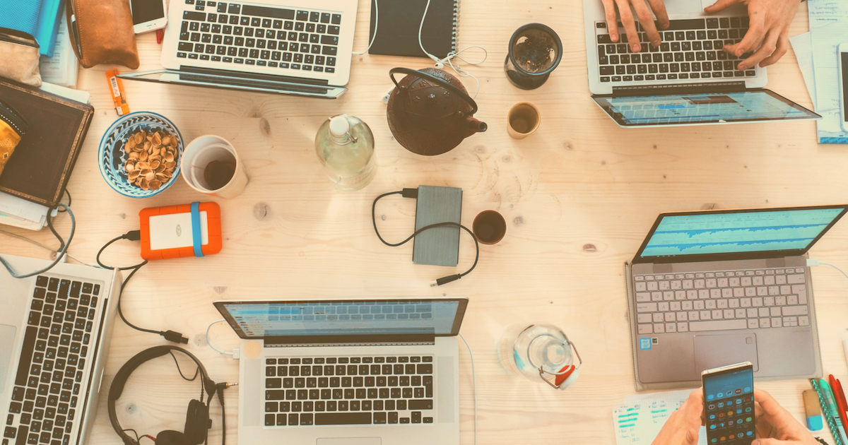 Top view of tabletop with laptops with accessories and people working