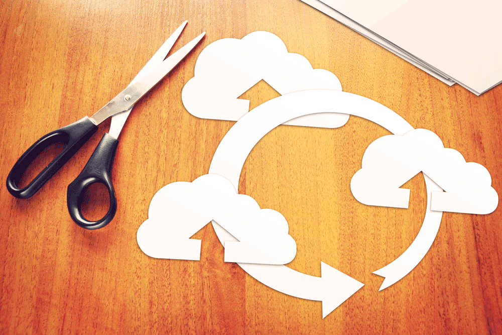 Clouds and arrow cut out on desk depicting cloud computing