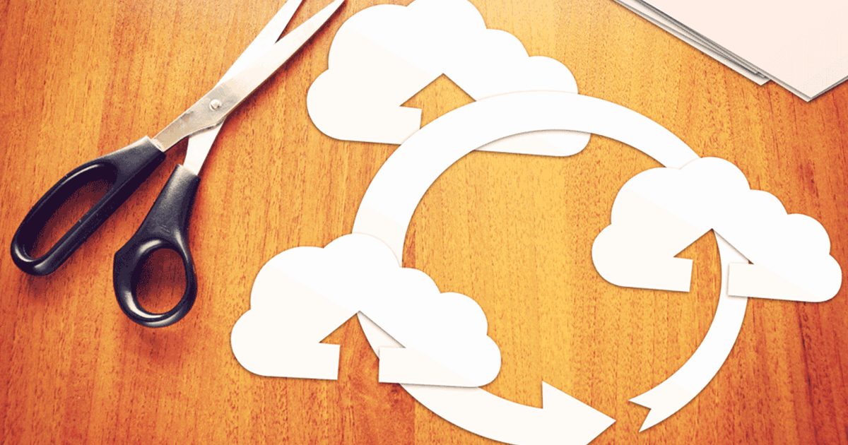 Clouds and arrow cut out on desk depicting cloud computing